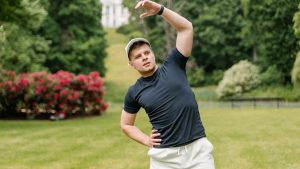 Man stretching in a park wearing a black shirt and white shorts, embracing a healthy lifestyle.